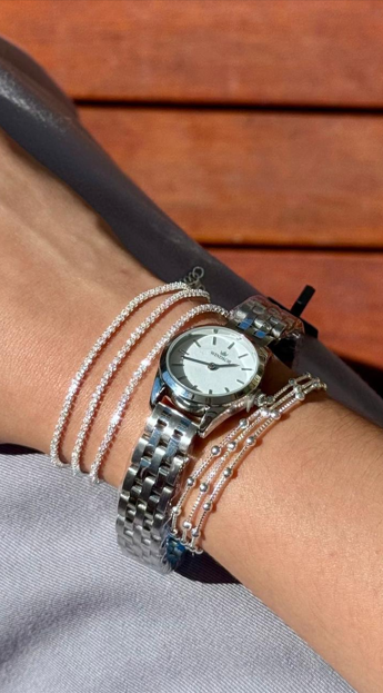 Relógio feminino prata Windsor com mostrador branco ao lado de mix de pulseiras com zircônias