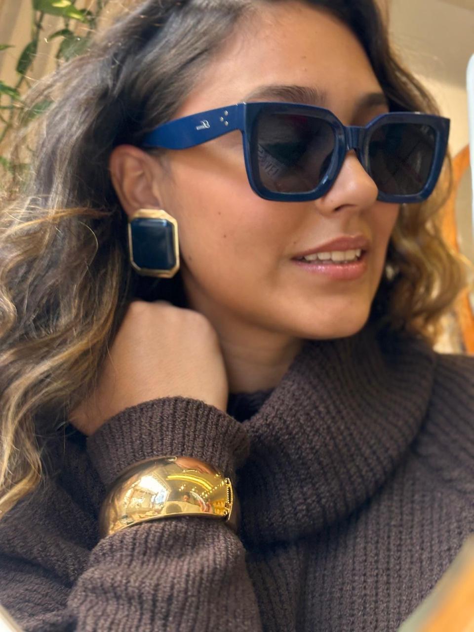 Óculos de sol azul-marinho geométrico, brinco quadrado azul com acabamento dourado e pulseira dourada larga